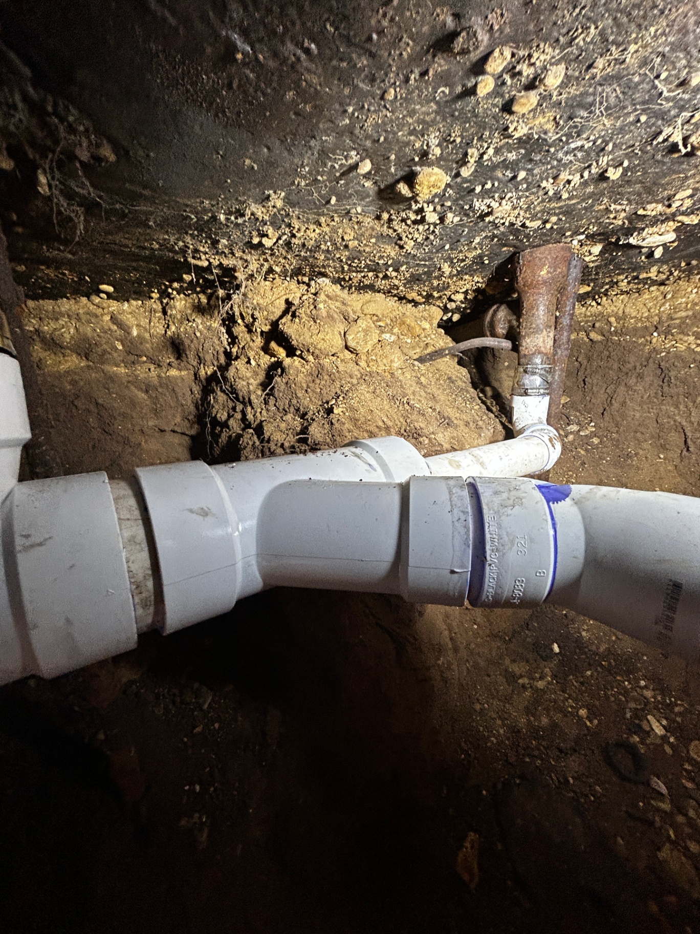 Conexión nueva de PVC instalada en túnel bajo losa para reparación de drenaje